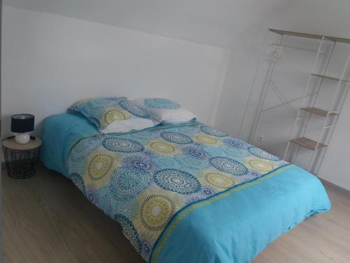een slaapkamer met een bed met een blauwe en gele deken bij Le Fort des Sables in Ambleteuse