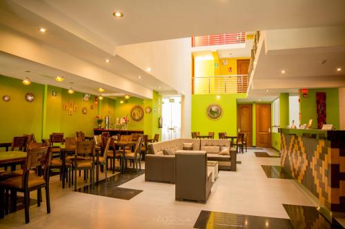 un restaurante con paredes verdes, sofá y sillas en Hotel Incamin Mirador, en Arequipa