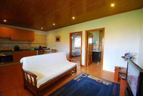 a living room with a white couch and a kitchen at Alojamentos Flores Island in Faja Grande