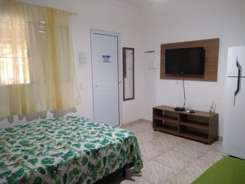 una camera con letto e TV a schermo piatto di Chalé Residencial Bosque da Cocanha a Caraguatatuba