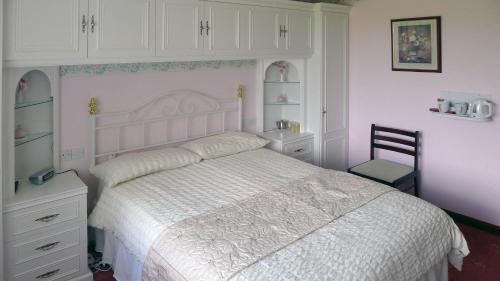 a bedroom with a white bed and a chair at The Sheiling in Laide