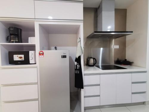 a white kitchen with a refrigerator and a sink at Mid Valley Southkey Mosaic Cozy Suite at Johor Bahru in Johor Bahru