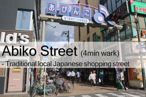 a city street with people walking on the sidewalk at Prestige Suites Osaka Abiko in Osaka