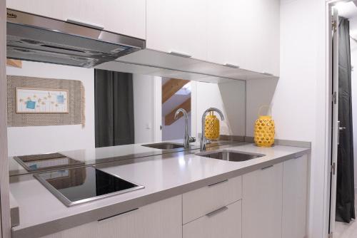 a white kitchen with a sink and a mirror at BeSalamanca in Salamanca