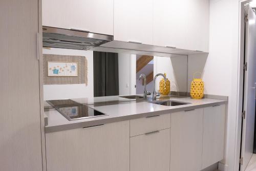 a white kitchen with a sink and a mirror at BeSalamanca in Salamanca