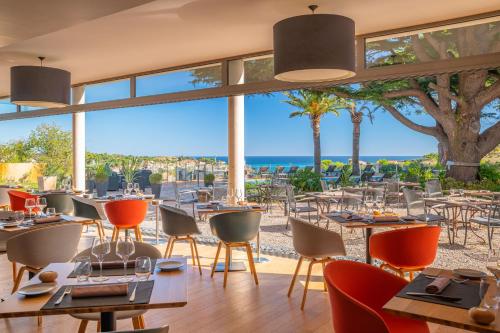 a restaurant with tables and chairs with the ocean in the background at Les Jardins Du Cèdre in Port-Vendres