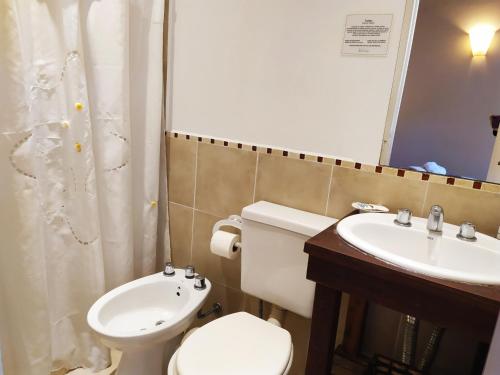 a bathroom with a white toilet and a sink at Hostería Costa Bonita in Villa Gesell