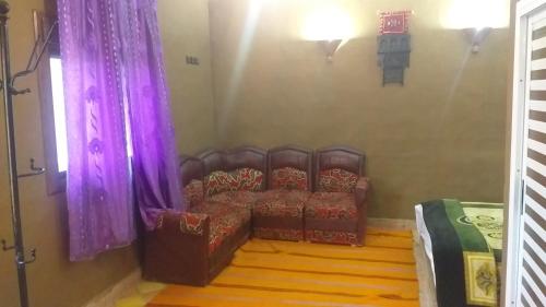 a living room with a couch and purple curtains at Auberge Camping BOUGAFER Tamtetoucht in Tamtetoucht