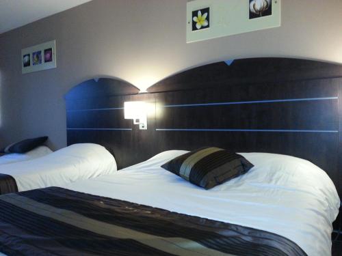 a hotel room with two beds and a large headboard at Hôtel Akena City Caudry in Caudry