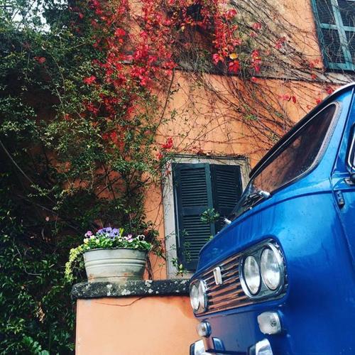 a blue car parked in front of a building with flowers at La Fontanella - Piccolo Appartamento nel Centro Storico di Nemi in Nemi