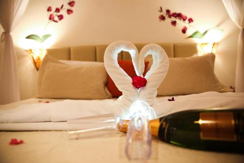 a bottle of wine and two swans on a bed at Xamã Senses - Hotel Pousada in Pipa