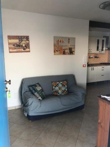 a blue couch in a living room with a kitchen at GIGLIO DI MARE Residence in Sellia Marina