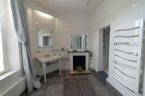 La salle de bains blanche est pourvue d'un lavabo et d'une cheminée. dans l'établissement Appartement de 2 Chambres au 1er Etage, à Carcassonne