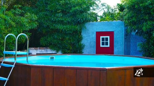 una bañera de hidromasaje en una valla con un árbol y una puerta roja en Quinta do Paraíso, en Porto Martins