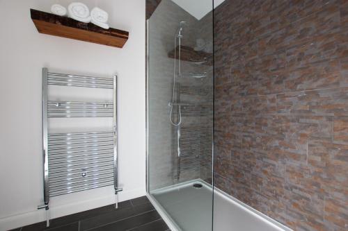 a bathroom with a glass shower with a brick wall at Millbrae Lodges in Belfast
