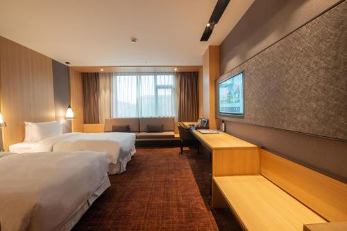 a hotel room with two beds and a television at Hotel Coka Chuansha Metro - Shanghai PVG Airport in Shanghai