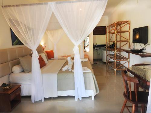 a bedroom with a bed with white drapes at Xamã Senses - Hotel Pousada in Pipa