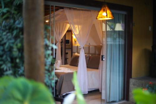 a view of a bedroom with a bed with curtains at Xamã Senses - Hotel Pousada in Pipa