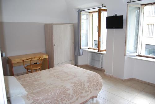 a bedroom with a bed and a desk and windows at Albergo della Posta in Trivero