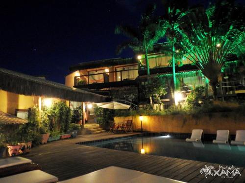 a building with a swimming pool at night at Xamã Senses - Hotel Pousada in Pipa