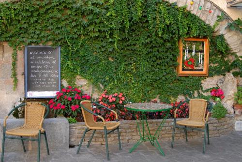 una mesa y sillas sentadas frente a una pared en Hostal Victor, en Oliana