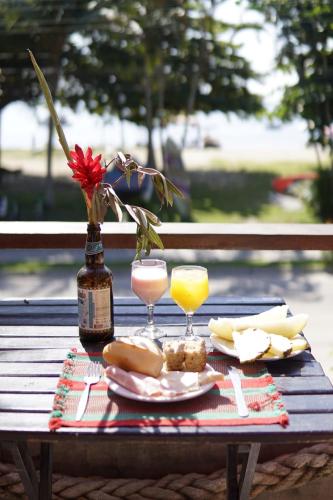 een picknicktafel met twee glazen sinaasappelsap en kaas bij Hostel Sereia do Mar in Paraty