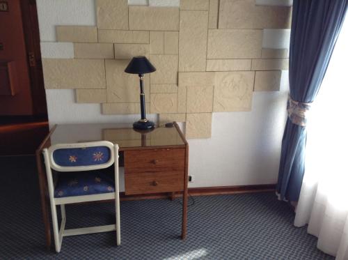 a desk with a lamp and a chair in a room at Hotel Alicante in Chillán