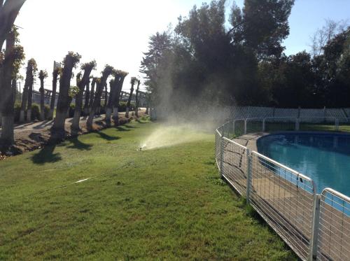 a hose spraying a yard with a swimming pool at Hotel Alicante in Chillán