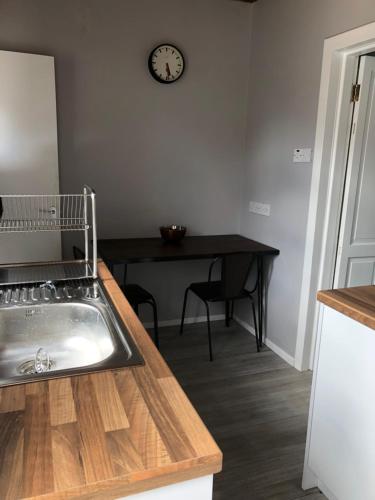 a kitchen with a sink and a table with a clock at Cosy home close to Bangor in Bangor