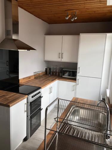 a kitchen with white cabinets and a dishwasher at Cosy home close to Bangor in Bangor