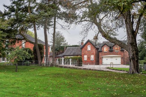 a large red brick house with a white garage at Woodleighton Cottages in Uttoxeter