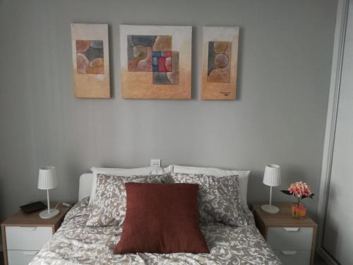 ein Schlafzimmer mit drei Gemälden an der Wand über einem Bett in der Unterkunft Cesar Augusto House in Saragossa