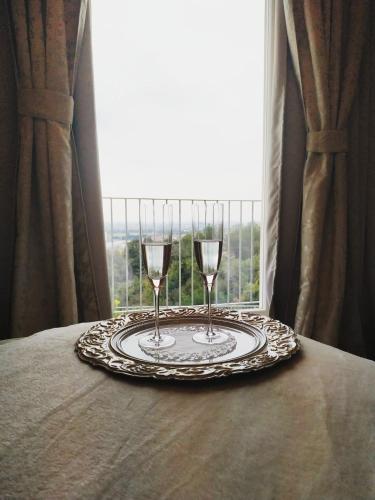 a plate with two glasses on a table with a window at B&B Villa Antilia in Busca