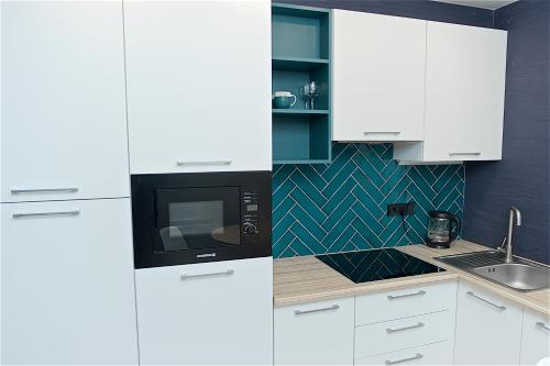 チェルカースィにあるСамая красивая квартира в Черкассах!の白いキャビネットと黒い電子レンジ付きのキッチンが備わります。