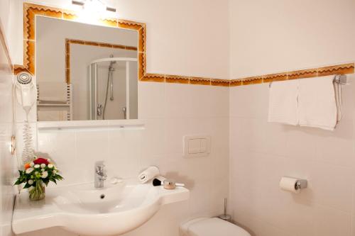 a bathroom with a sink and a toilet and a mirror at Hotel-Garni Appartement Gartenheim in Schenna