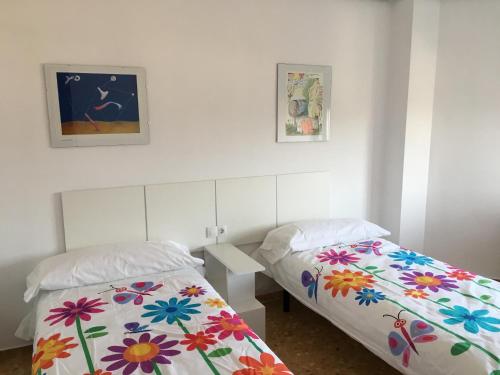 two beds in a white room with flowers at 380 Delicia de Teruel in Teruel