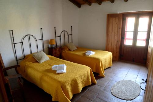 a room with two beds with yellow sheets and a window at Casa Do Alto Da Eira in Albergaria dos Fusos
