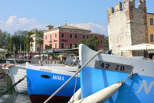 two boats are docked in the water next to buildings at Hotel Alla Riviera in Bardolino