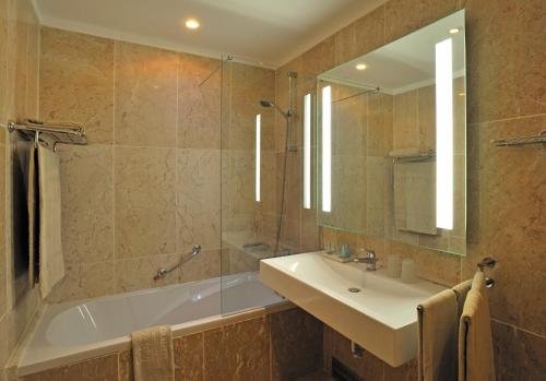 a bathroom with a tub and a sink and a mirror at Pestana Viking Beach & SPA Resort in Armação de Pêra