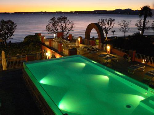 a green swimming pool with a view of the water at Hotel Alla Riviera in Bardolino