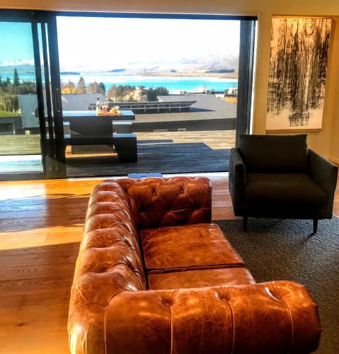 a brown leather couch in a room with a large window at The View Lake Tekapo in Lake Tekapo