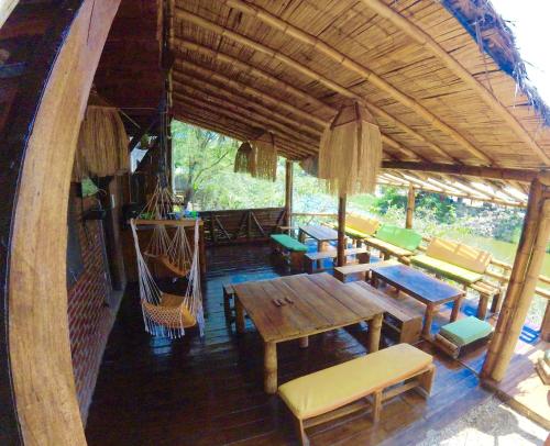 een patio met houten tafels en stoelen bij Iguana Beach House in Montañita