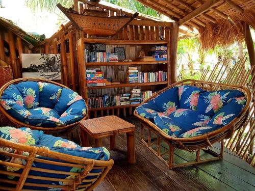 una biblioteca con 2 sillas y una estantería con libros en Amami Beach Resort en Puerto Galera