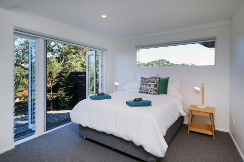 a bedroom with a large bed and large windows at Waiheke Island Vineyard Holiday Houses in Surfdale