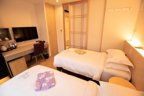 a hotel room with two beds and a desk at SOLA HOTEL in Tokyo