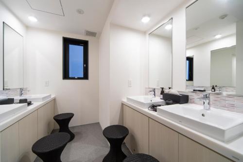 a bathroom with two sinks and two black chairs at Grids Tokyo Ueno Hotel&Hostel in Tokyo