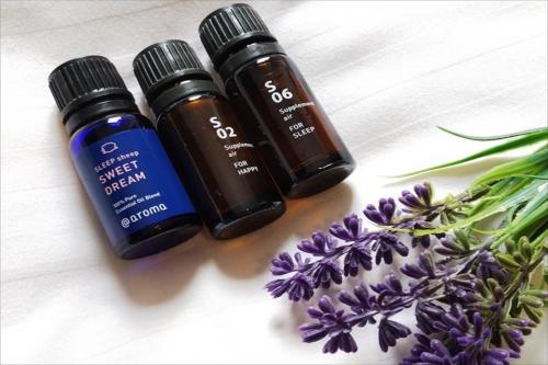 three bottles of essential oils next to a bunch of flowers at Green Rich Hotel Iwakuni Ekimae (Artificial hot spring Futamata Yunohana) in Iwakuni