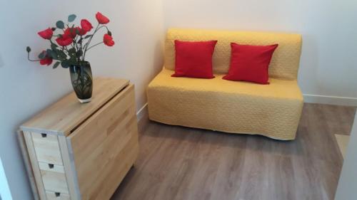 Un dormitorio con una cama amarilla con almohadas rojas y un jarrón de flores en Paris 8 ème Appartement 2 pièces Métro Miromesnil, en París