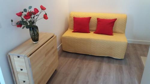 une chambre avec un lit jaune avec des oreillers rouges et un vase de fleurs dans l'établissement Paris 8 ème Appartement 2 pièces Métro Miromesnil, à Paris