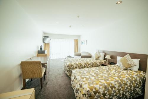 Habitación de hotel con 2 camas y sofá en Airport Delta Motel en Christchurch